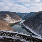 Snow-covered mountains surrounding the New River with a bridge