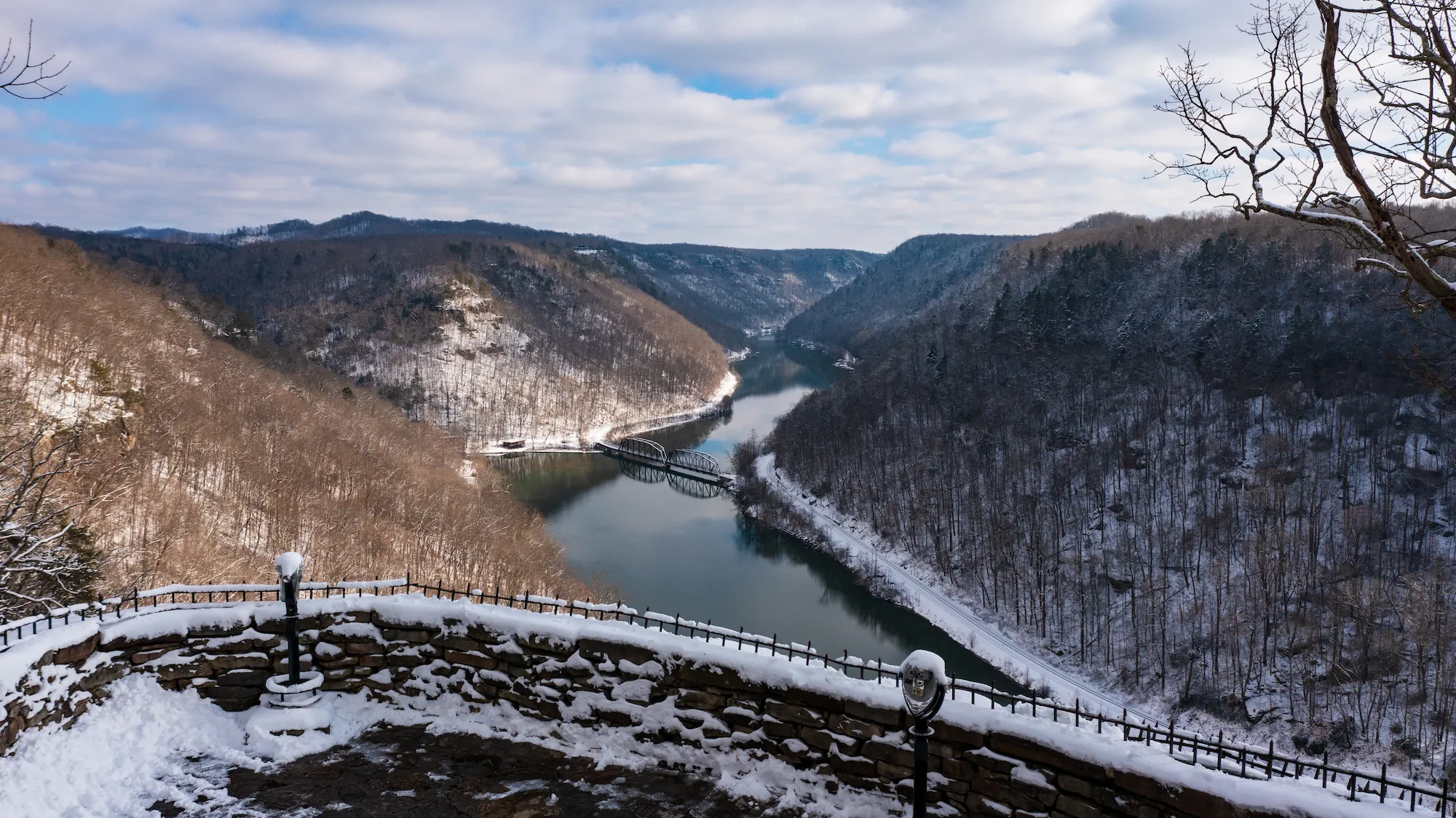 Snow-covered mountains surrounding the New River with a bridge