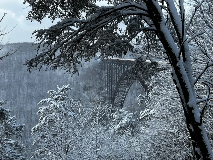 New River Gorge Bridge spanning a snowy gorge framed by snow-covered trees