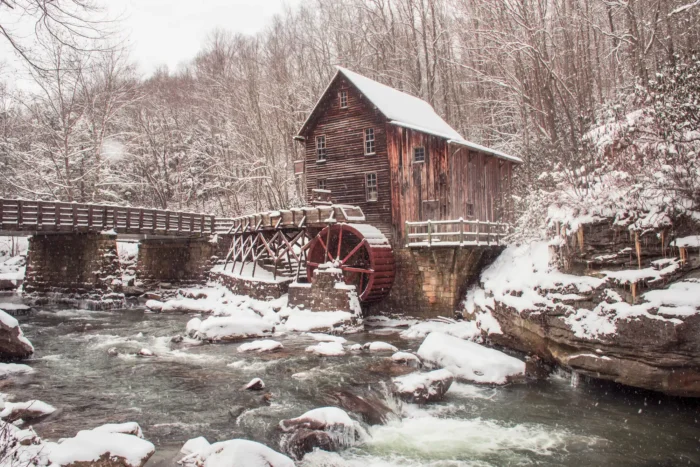 Glade Creek Grist Mill at Babcock State Park beside a snow-covered stream in winter