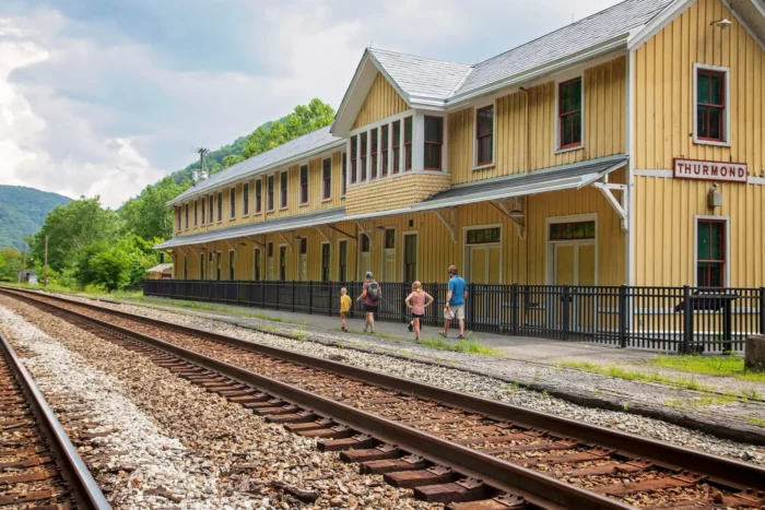 A family walks between the railroad and the Thurmond Train Depot.