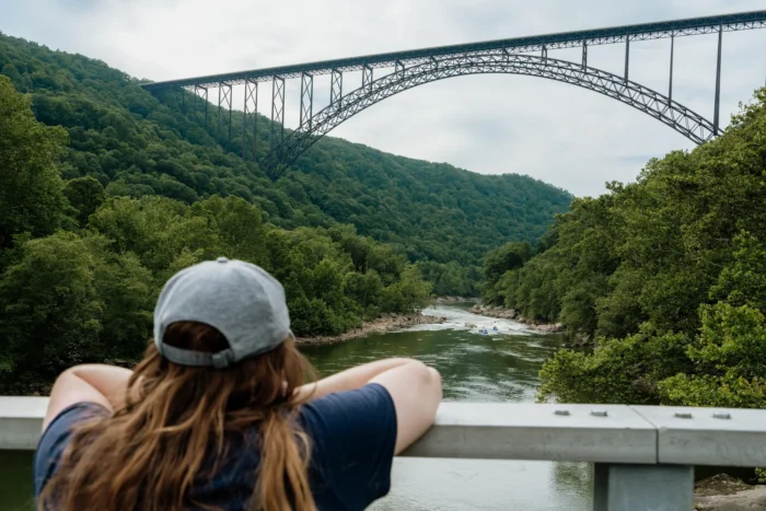 A woman admiring the view of the New River Gorge Bridge from below on Fayette Station Road.